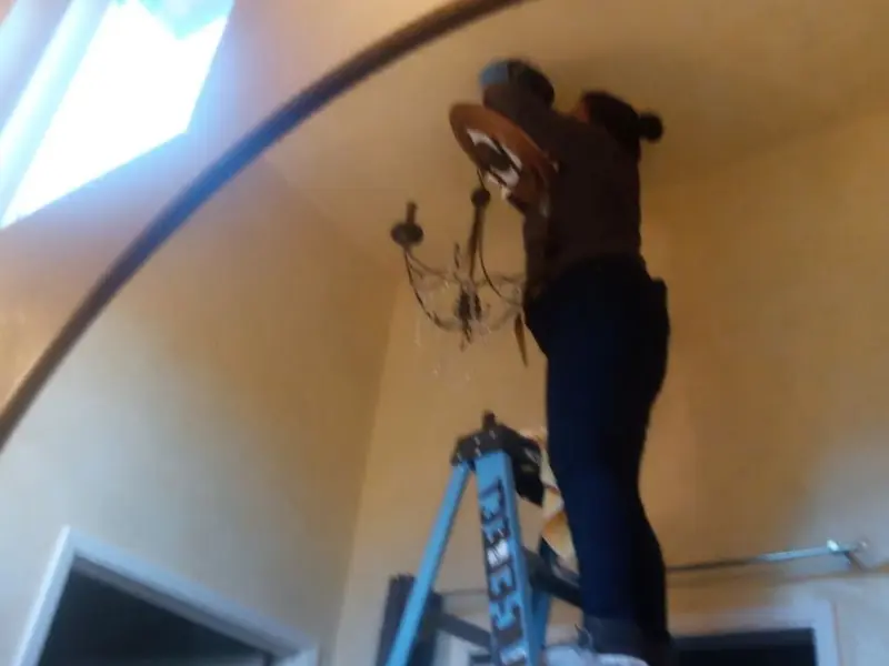 Electrician installing a chandelier in a Cumberland residence